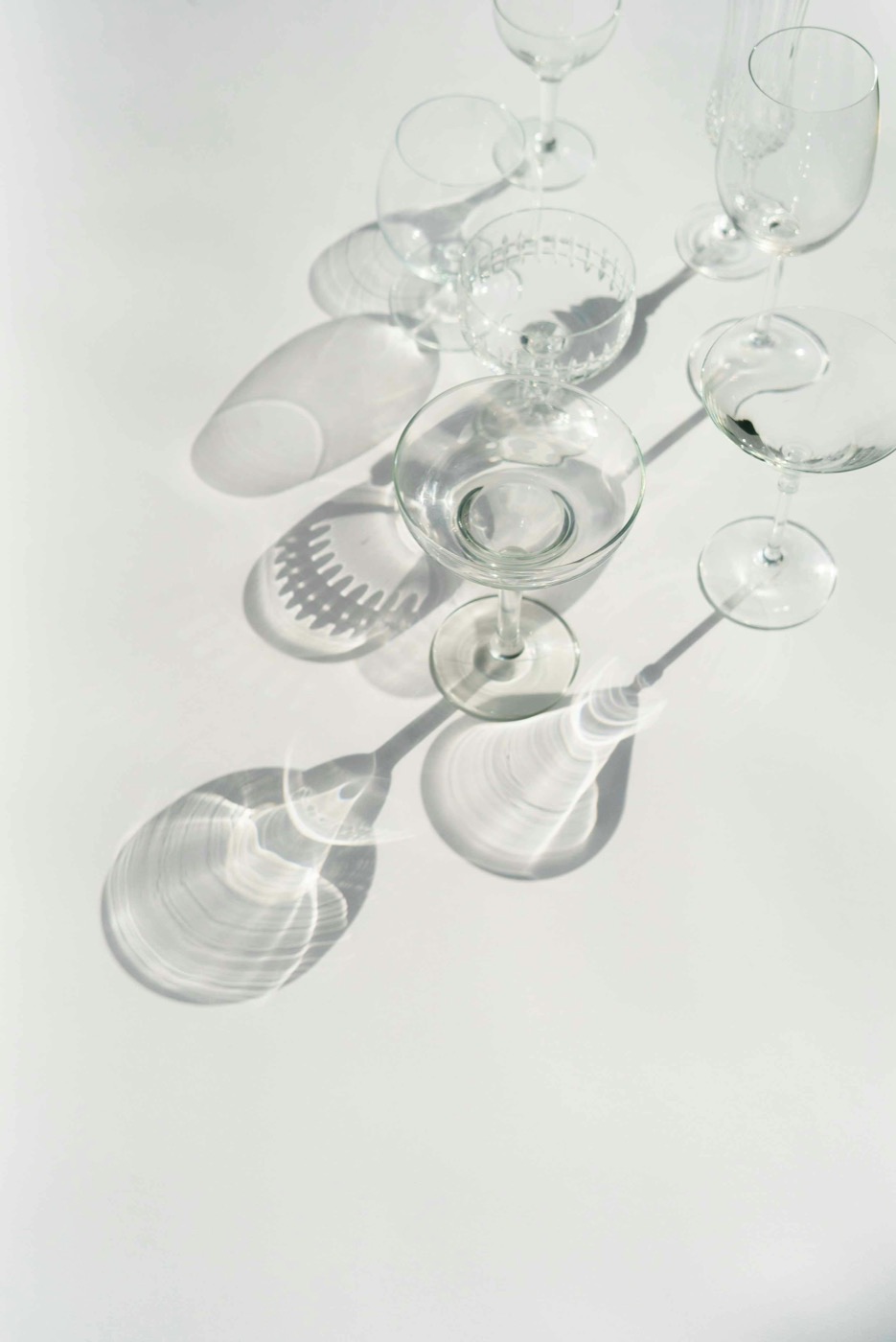 Empty crystal glasses casting caustic shadows in raking light