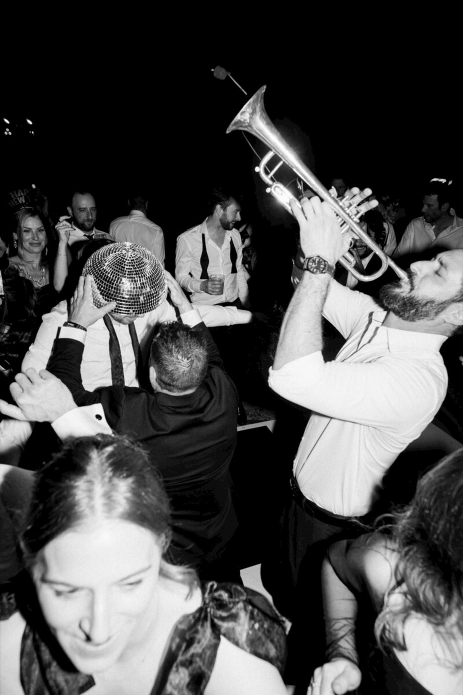 A trumpet player blasting into a packed late-night crowd, a disco ball in the throng