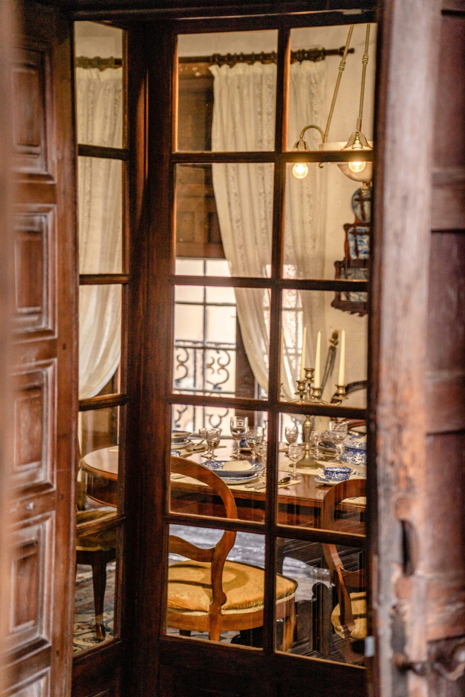 The set dining table seen through panelled glass doors, candlelit