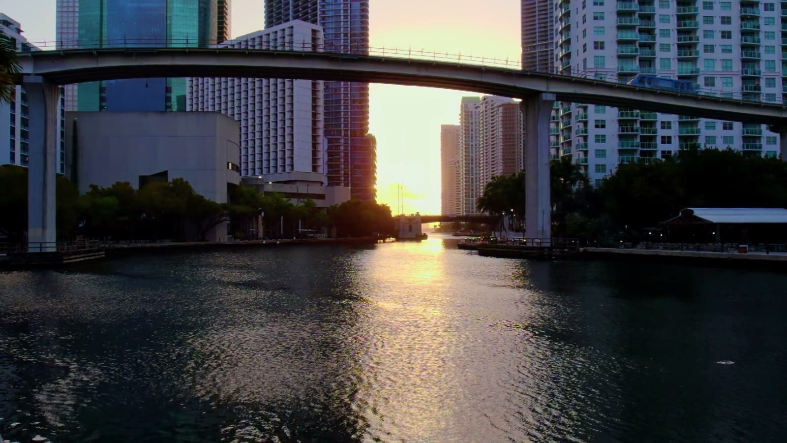 A city skyline at golden hour over the bay, light gliding past the glass towers