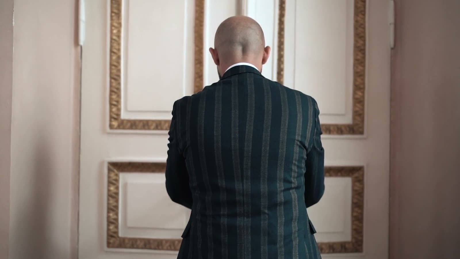 A figure in a tailored suit in a softly lit panelled room
