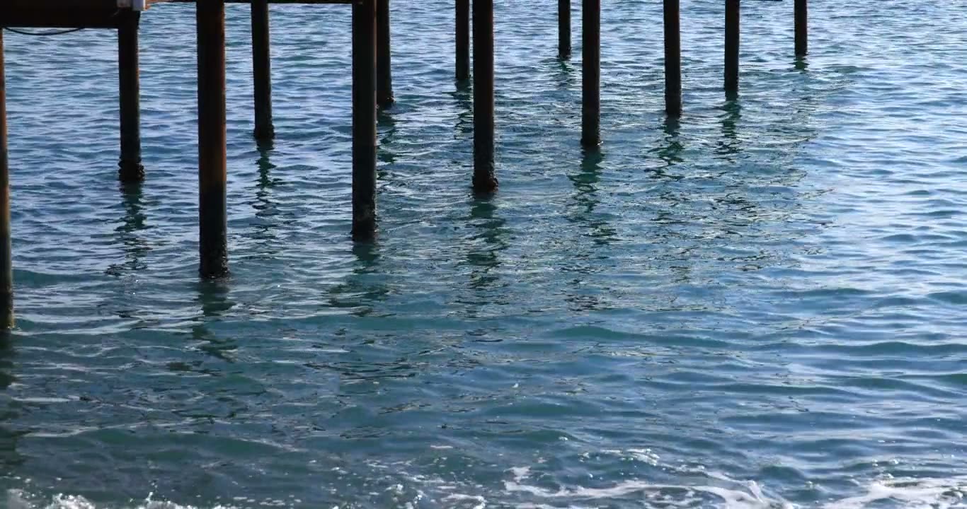 Clear water lapping the dark pilings of a seaside dock